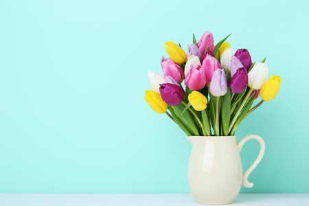 Bouquet of tulips in jug on wooden tableの写真素材