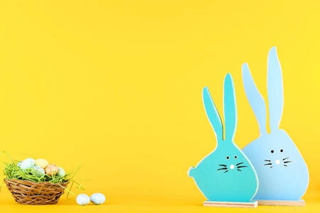 Easter eggs and wooden rabbits on yellow backgroundの写真素材