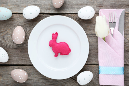 Kitchen cutlery with easter eggs and fabric rabbit on wooden table