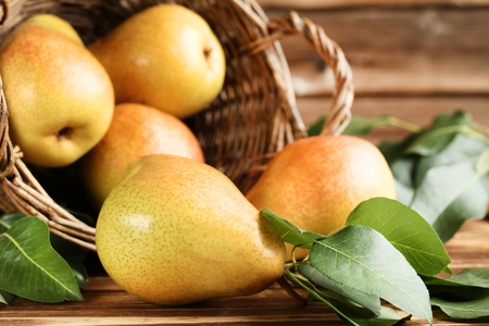 Ripe pears and green leafs on brown wooden tableの写真素材