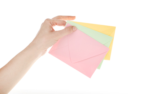 Female hand with colorful paper envelopes on white backgroundの写真素材