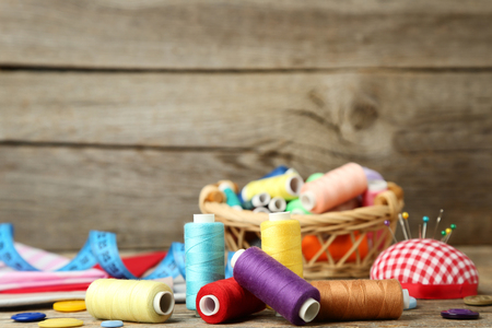 Colored threads with sewing accessories on grey wooden tableの写真素材