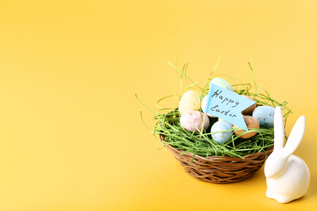 Colorful eggs with white rabbit and text Happy Easter on yellow backgroundの写真素材