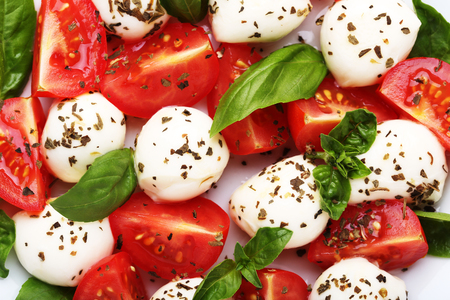 Mozzarella, tomatoes and basil leafs on white plateの写真素材