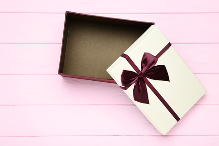 Open gift box on pink wooden table