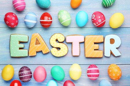 Colorful eggs with word Easter on wooden table