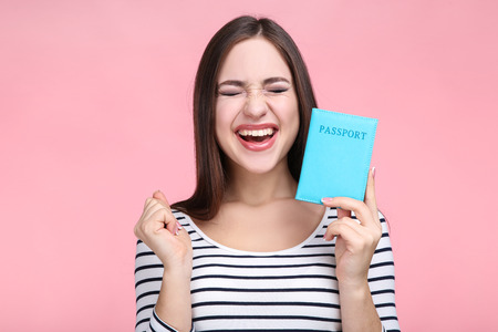 Beautiful young woman with passport on pink backgroundの写真素材
