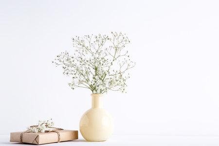 White gypsophila flowers in vase with gift box on grey backgroundの写真素材