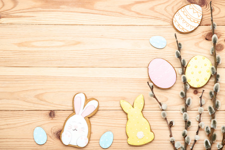 Easter gingerbread cookies with willow branches on brown wooden table