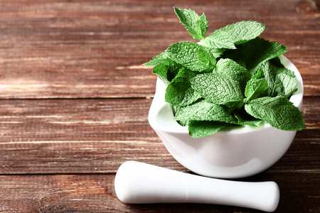 Mint leafs with mortar on brown wooden tableの写真素材