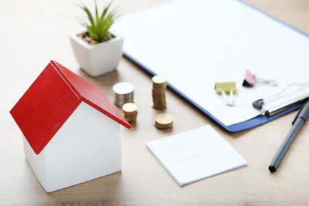 House model with coins and paper on brown wooden tableの写真素材