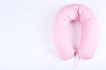 Pink body pillow on white bed backgroundの写真素材