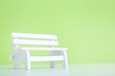 Small white wooden bench on green backgroundの写真素材