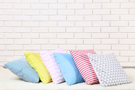 Soft colorful pillows on brick wall backgroundの写真素材