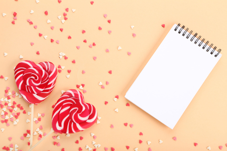 Heart shaped lollipops with sprinkles and notebook on beige backgroundの写真素材
