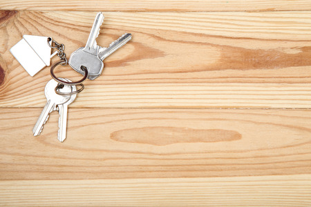 Silver keys with house symbol on brown wooden tableの写真素材