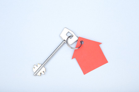 Silver key with paper house on grey backgroundの写真素材