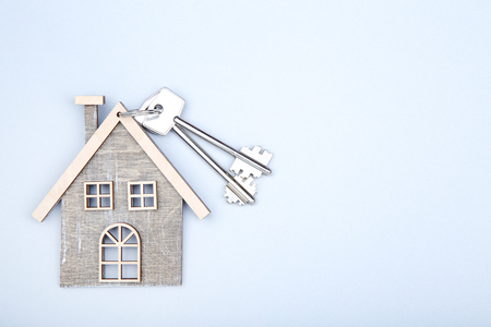 Silver keys with wooden house on grey backgroundの写真素材