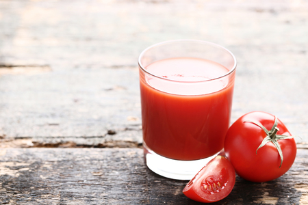 Tomato juice in glass on grey wooden tableの写真素材