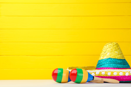 Mexican hat and maracas on yellow background