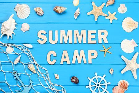 Text Summer camp with seashells and fishing net on blue wooden tableの写真素材