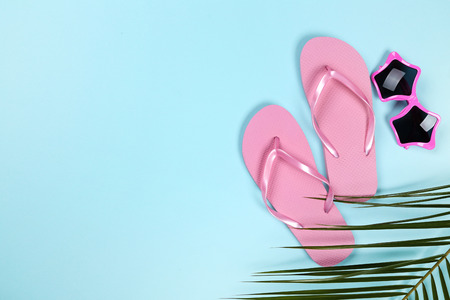 Pair of flip flops with sunglasses and palm leafs on blue backgroundの写真素材