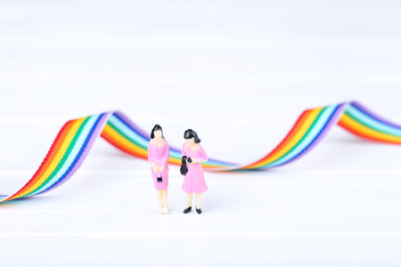 Miniature people with rainbow ribbon on white backgroundの写真素材