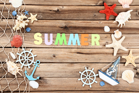 Word Summer with seashells and fishing net on brown wooden tableの写真素材