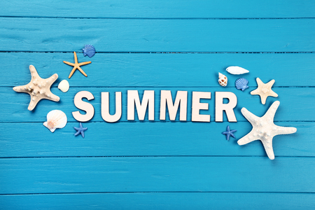 Word Summer with seashells on blue wooden tableの写真素材