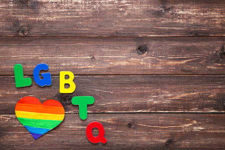 Abbreviation LGBT with rainbow heart on brown wooden tableの写真素材