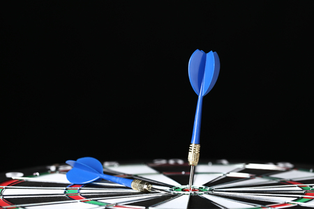 Dartboard with darts on black backgroundの写真素材