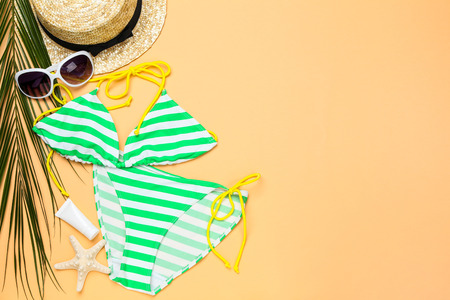 Fashion swimsuit with palm leaf and sunglasses on beige backgroundの写真素材
