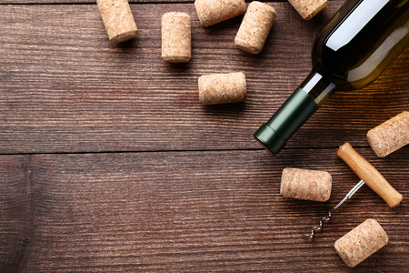 Wine bottle with corks and corkscrew on brown wooden tableの写真素材
