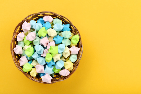Colorful paper stars in basket on yellow background