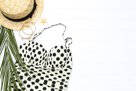 Fashion swimsuit with starfish, hat and palm leaf on white wooden tableの写真素材