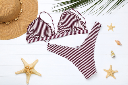 Fashion swimsuit with starfishes and hat on white wooden tableの写真素材