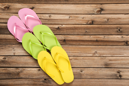 Pairs of colorful flip flops on brown wooden tableの写真素材