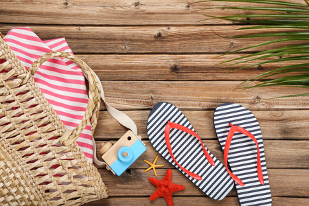 Pair of flip flops with starfish and wooden camera on brown tableの写真素材