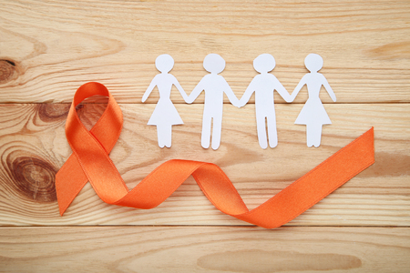 Orange ribbon on wooden table. Medicine conceptの写真素材