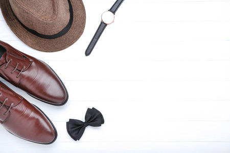 Male leather shoes with hat, wrist watch and bow tie on white backgroundの写真素材