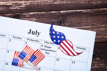 Text Happy Independence Day in calendar with american flags and mustache on wooden tableの写真素材
