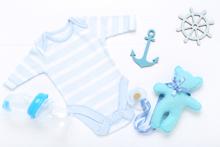 Baby clothes with soft toy and soother on white backgroundの写真素材