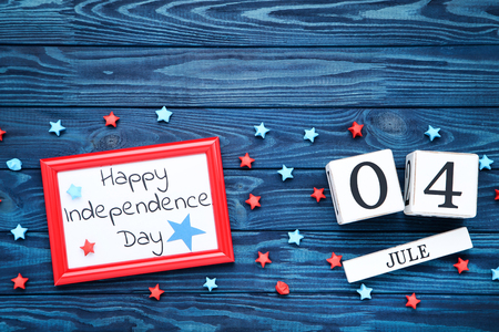Text Happy Independence Day with paper stars and cube calendar on blue wooden tableの写真素材