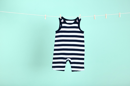 Baby clothes hanging on blue backgroundの写真素材