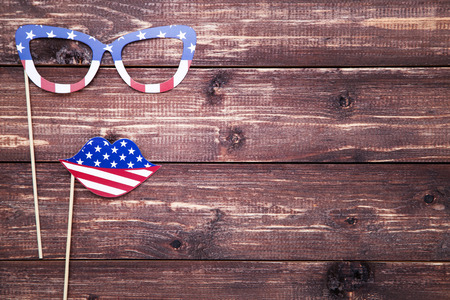 American flag in paper glasses and lips on brown wooden tableの写真素材