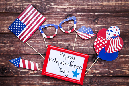 Text Happy Independence Day with american flag in glasses, lips and balloons on brown wooden tableの写真素材