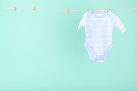 Baby clothes hanging on blue backgroundの写真素材