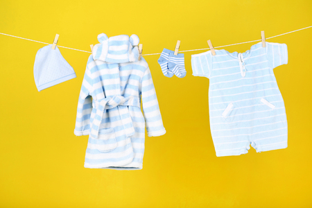 Baby clothes hanging on yellow backgroundの写真素材