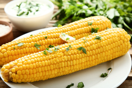 Fresh corn with parsley and butter on wooden tableの写真素材