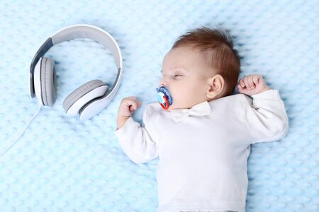 Cute baby sleeping in bed near headphonesの写真素材